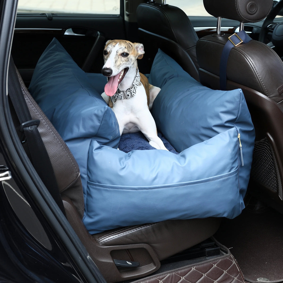 Whippet sitting in the navy petsperro dog car seat on a car back seat, held by the headrest strap